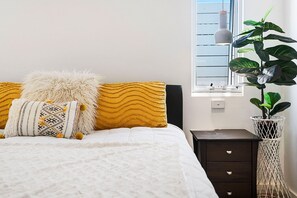 Unwind in this inviting bedroom, adorned with a cozy bed, plush pillows, and a touch of natural light filtering through the window.