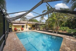 Screened Lanai with Salt Water Pool and Seating Area surrounded by lush gardens.