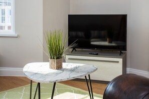 A sleek centre table adorned with fresh flowers serves as the focal point, inviting you to gather around for lively conversations or cozy movie nights.