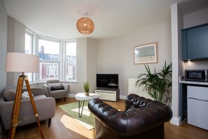 Supplementary wall art adds a touch of personality to the space, while tripod lamps cast a warm glow, creating the perfect atmosphere for unwinding after a day by the sea.