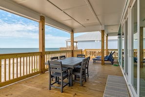 Gather around the outdoor dining table and enjoy meals with panoramic ocean views. This spacious covered deck is perfect for relaxing and entertaining by the beach.