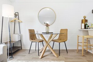 Gather around the stylish dining area with a round table and chairs, a large mirror, and a sleek floor lamp.
