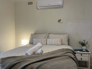 Relax and unwind in this comfortable bedroom, complete with a cozy bed and a touch of greenery. The air conditioning will ensure a restful night's sleep.