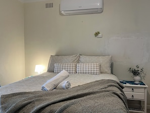 Relax and unwind in this comfortable bedroom, complete with a cozy bed and a touch of greenery. The air conditioning will ensure a restful night's sleep.