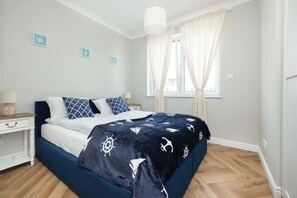 A cozy bedroom with nautical-themed bedding, soft curtains, and a bright ambiance.

