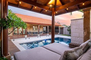 Seating overlooking the pool under bali inspired cabana 