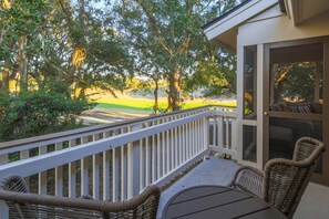 The back porch and screened porch feature views of the golf course and lush, Lowcountry trees.