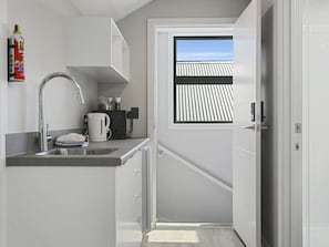 Kitchenette equipped with a fridge/freezer, toaster, jug, microwave, and kitchen utensils and cutlery