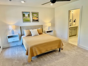 MASTERS BEDROOM – This spacious primary bedroom features a plush bed with a neutral, striped comforter that creates a calming and comfortable ambiance. The room is well-lit with natural light from large windows and a private door leading to the outside. Modern artwork adorns the walls, giving the space a personalized touch. The sleek ceiling fan adds to the room's airy feel, wh...