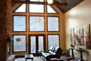 The great room has soaring wood ceilings, beams, and mountain views