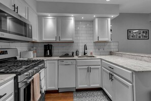 Fully stocked kitchen with pots/pans, dishwasher, coffee machine, and toaster