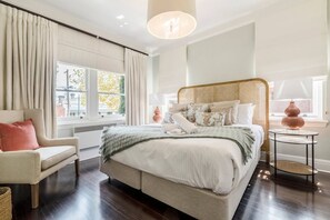  Unwind in the chic primary bedroom, featuring a king-sized bed and stylish rattan headboard.