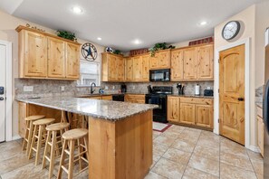 Savor the charm of this well-appointed kitchen adorned with warm oak cabinets, complemented by a large barstool dining area.