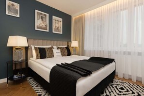 Cozy bedroom with a teal accent wall, black-and-white bedding, patterned rug, and plenty of natural light.

