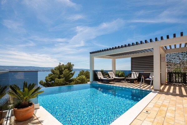 Astonishing sea view from the terrace with heated pool and deck chairs for relaxing in luxury villa for rent Holiday Residence