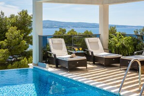 Deck chairs by the hetaed pool in rental villa Holiday Residence for families and friends