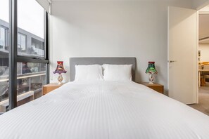 A well-sized bedroom offers loads of light through the wall-length windows and has a plush double bed and built-in mirrored wardrobes