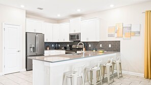 Bright modern kitchen with sleek appliances, a large island, and a stylish backsplash.