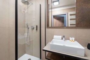 Modern bathroom with glass shower, beige tiles, and elegant sink.

