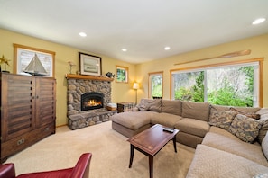 Living room with Gas Fireplace, cable TV, large cozy couch, open to kitchen and dining room.