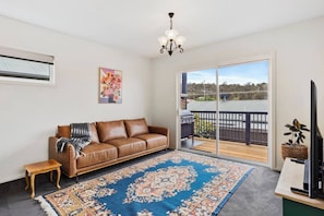 Experience the airy upstairs living room, seamlessly connected to the balcony. Enjoy the breeze and natural light flooding in through the large glass doors. 