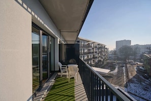 Balcony with city view, artificial grass, and outdoor seating.