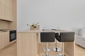 Kitchenette with wooden cabinets, bar stools, and dining area.