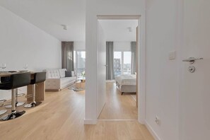 Open hallway leading to a bright living area with wooden flooring.