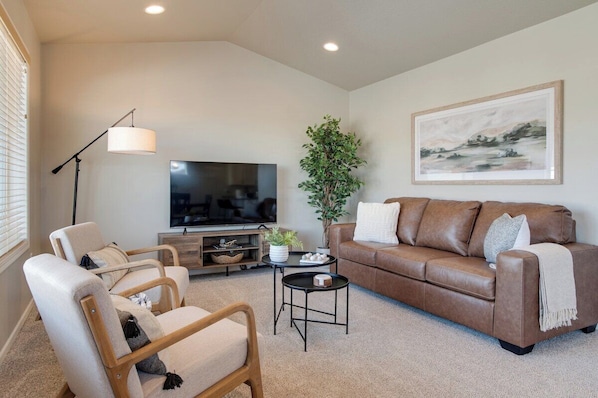 Relax in warmth and comfort of our upstairs living room, featuring a leather couch, two accent chairs, plush accent pillows, and a 58-inch Smart TV for your entertainment.