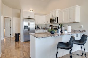 Fully stocked kitchen with seating for two at the bar, ideal for enjoying meals or chatting while cooking.