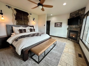 The master bedroom is complete with plush bedding, a luxurious area rug and an electric fireplace.