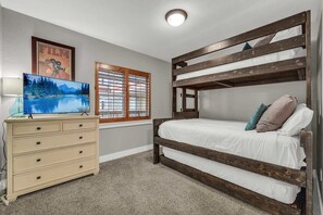 A guest bedroom makes efficient use of its space with a twin-over-queen bunk bed that includes a full-size trundle bed!