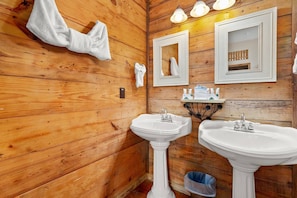 Indulge in rustic luxury in the charming bathroom adorned with wood shiplap walls and dual vanities, offering a tranquil retreat.