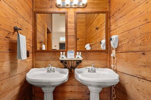 Indulge in rustic luxury in the charming bathroom adorned with wood shiplap walls and dual vanities, offering a tranquil retreat.