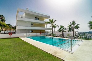 Lovely community pool surrounded by grass and Mediterranean plants