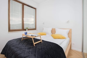 Bedroom with double bed, yellow accents, and large wooden window shutters.
