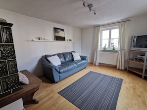 Wohnzimmer mit Ledersofa (Schlaffunktion), Kachelofen und Fernseher