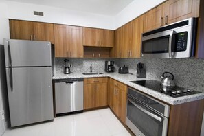 Fully equipped kitchen with a microwave, stove, oven, and fridge. All utensils, plates, and glasses are provided