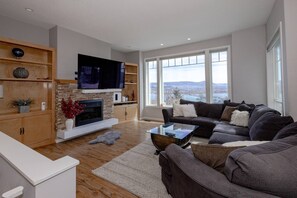 Living room with big screen tv, gas fireplace, panoramic views of lake and city