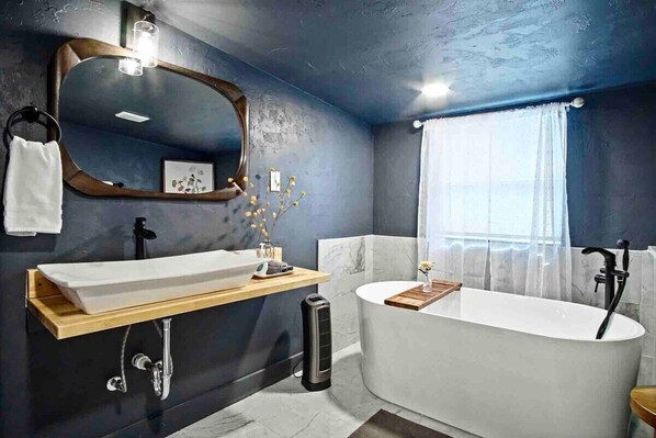A standard bathroom with Bathtub ready for a soak and Vanity mirror reflecting light

