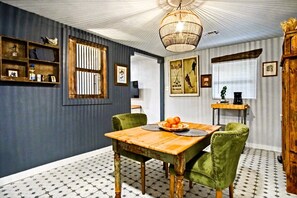 A wooden table and green chairs in the center of the kitchen, the large window lets in plenty of natural light, creating a warm and inviting atmosphere 