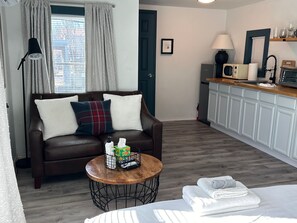 A cozy living room with a couch, coffee table next to a open kitchen