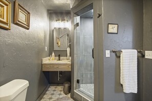 A bathroom with a white clawfoot tub, patterned floor tiles, and a framed print hanging on the wall. 
