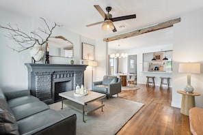 Gather in style. The modern fireplace and natural wood beam add warmth and character to this open-concept living space.