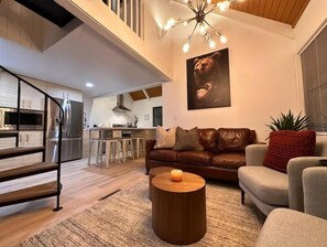 Living room, looking into kitchen. Stairs lead to upstairs loft bedroom.