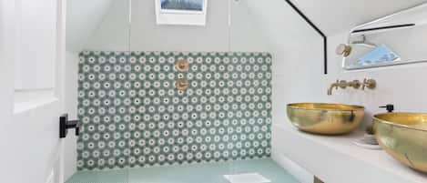 Luxury under the eaves—step into a one-of-a-kind designer bathroom with double rain showers, bold tile, and gold vessel sinks. Click through to explore the rest of this unforgettable stay.