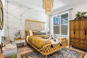 Boho-chic bedroom with a natural rattan frame, upscale linens, and blackout curtains—your peaceful Midtown retreat awaits.