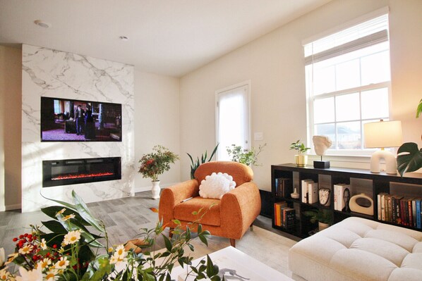 A spacious living room with a modern electric fireplace and a Netflix TV.