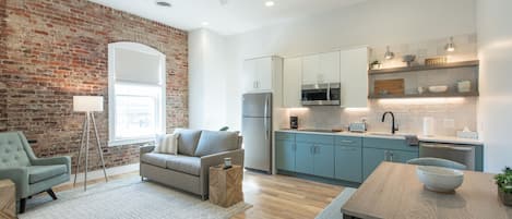 Open living area with full kitchen, dining area, work desk, and queen sleeper.