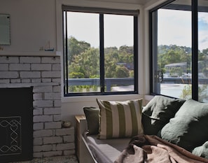 A cozy corner: sofa, a fireplace, cushions, blanket and a view